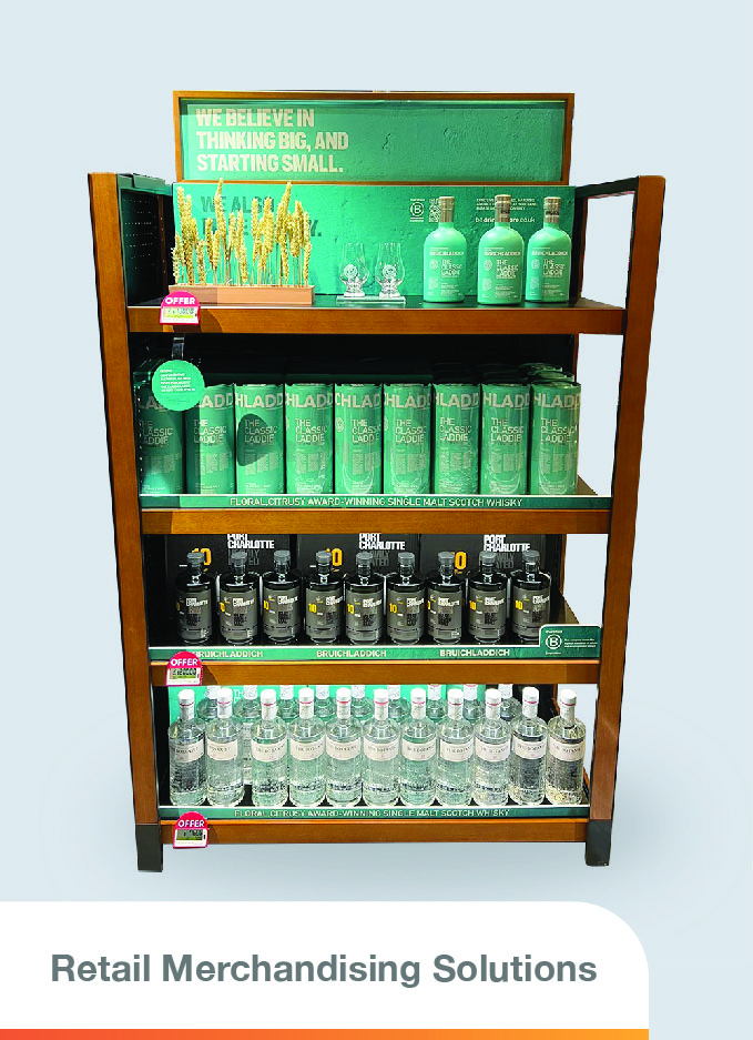 An organized display of alcohol bottles and decorations from dry wheat and two whisky glass on a shelf.