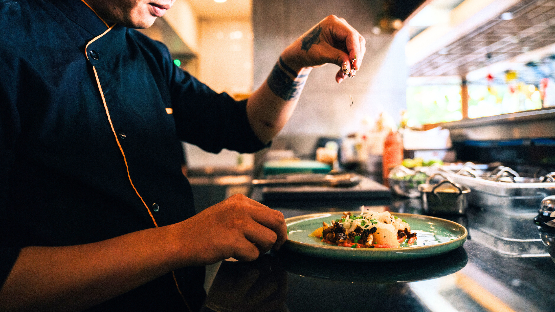 Chef plating a dish in a professional restaurant kitchen 