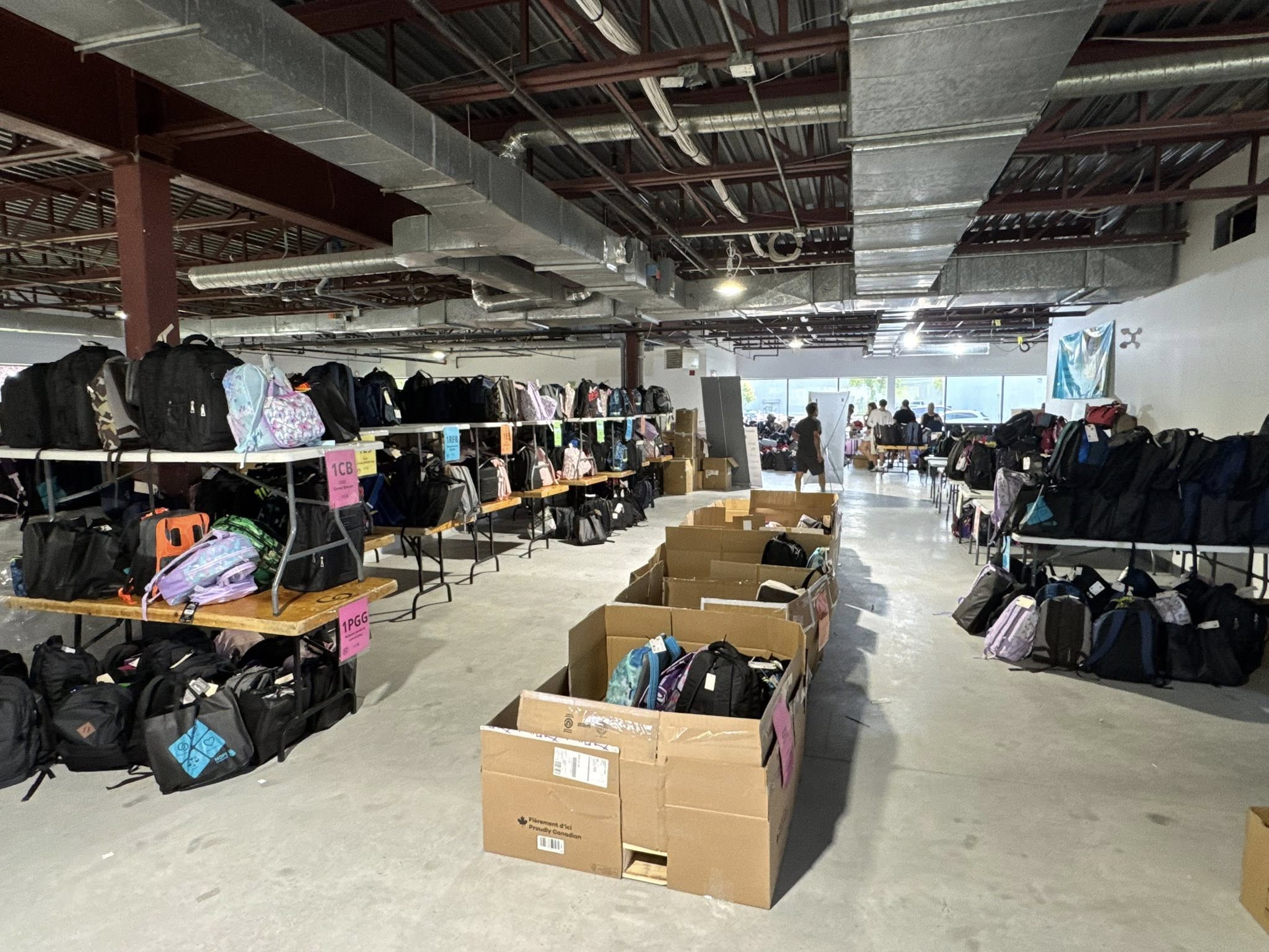 a group of people placing school bags in delivery bins