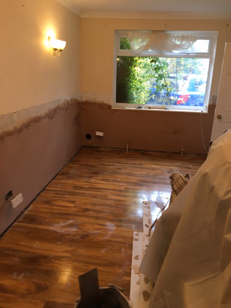 A room with new wooden flooring and partially plastered walls ready for further renovation.
