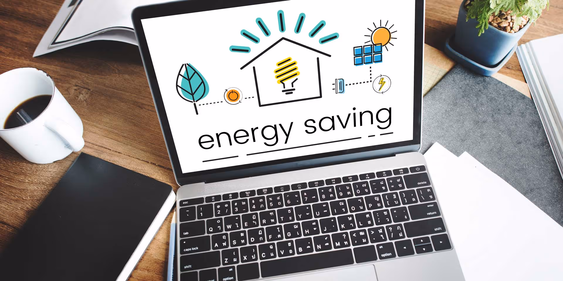 Open laptop displaying "energy saving" graphic with lightbulb and eco-friendly icons on screen.