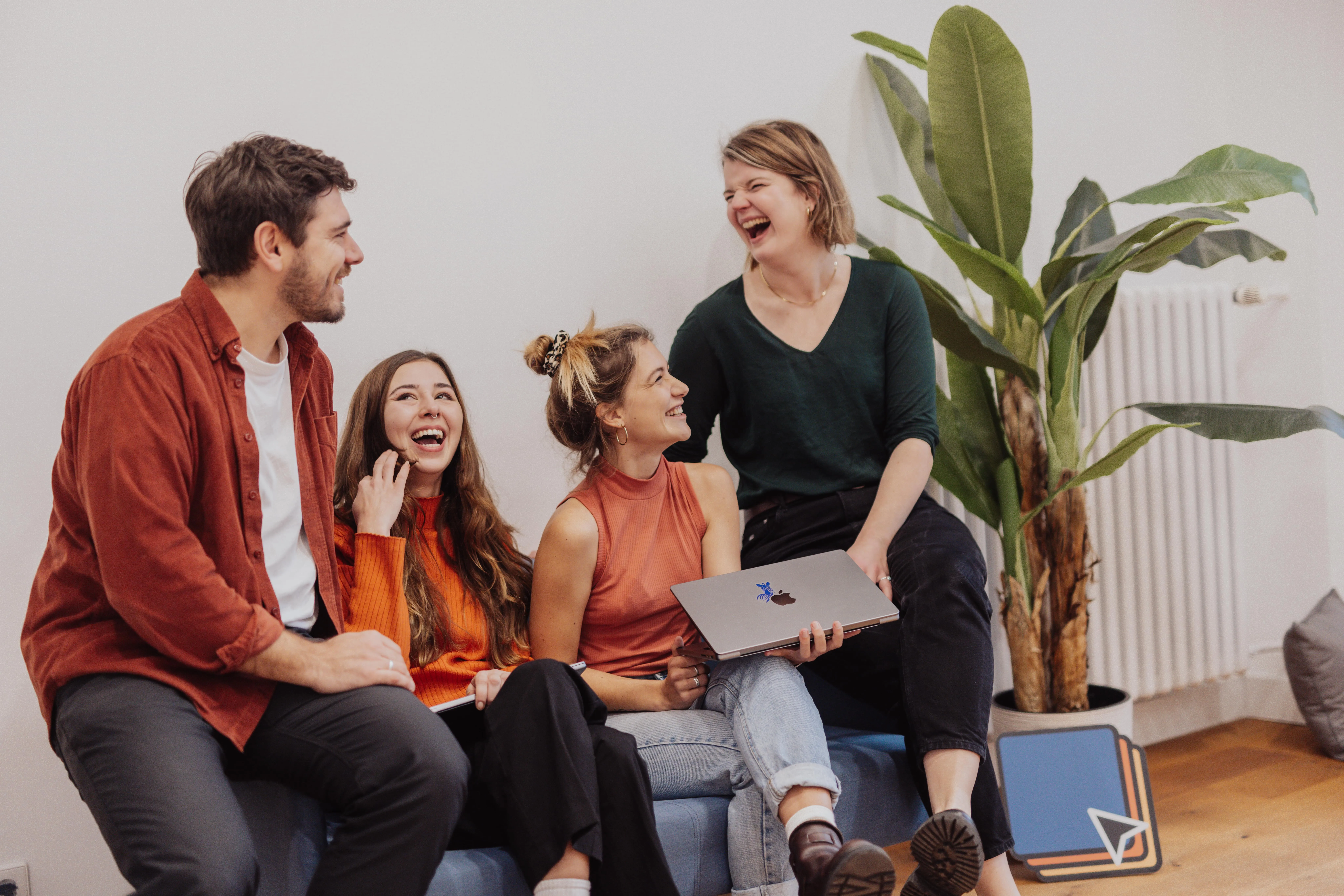 team laughing about something while holding a laptop