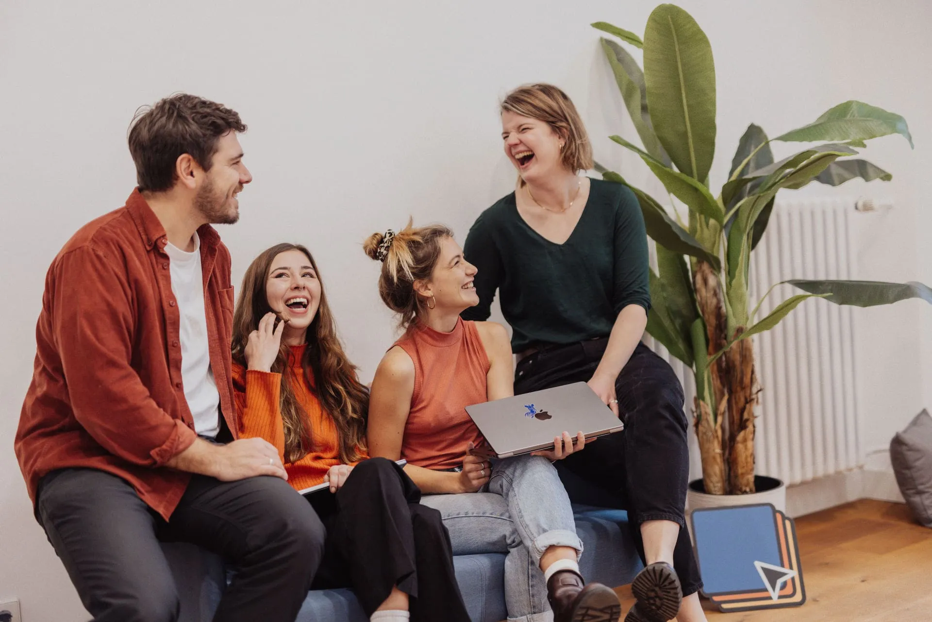 team laughing about something while holding a laptop