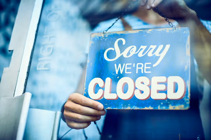 Waiter hanging closed sign on glass window