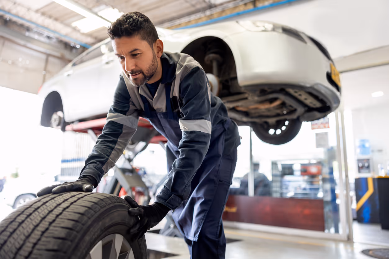 Happy mechanic changing a flat tire on a car - new hampshire auto repair shop insurance concept
