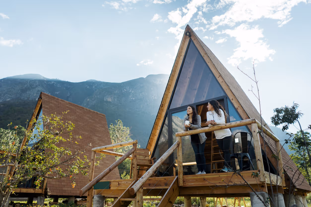Two female friends enjoying hot drink outside of cabin - airbnb insurance concept