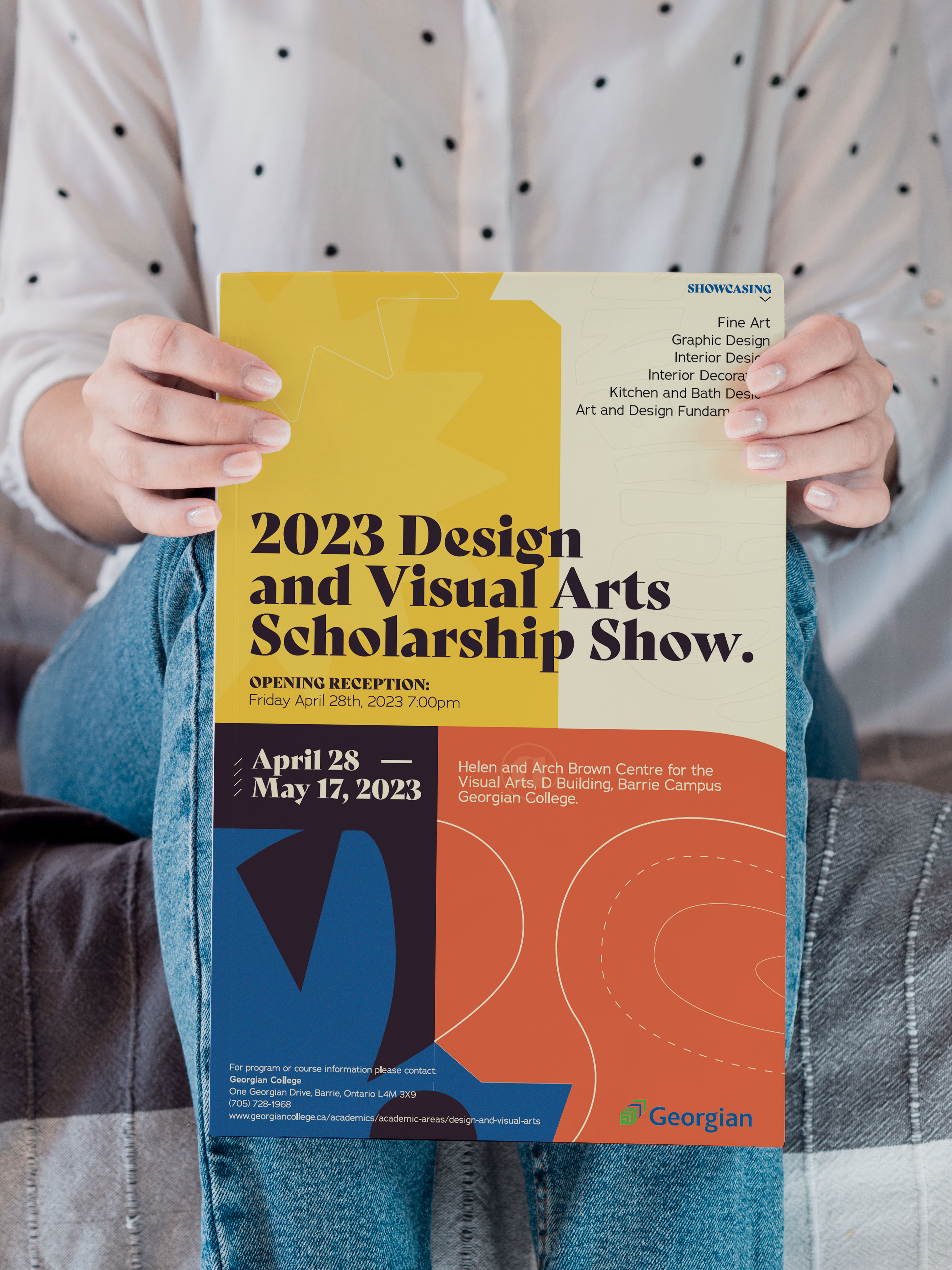 A woman in jeans and a white button-up holding the Design and Visual Arts poster.