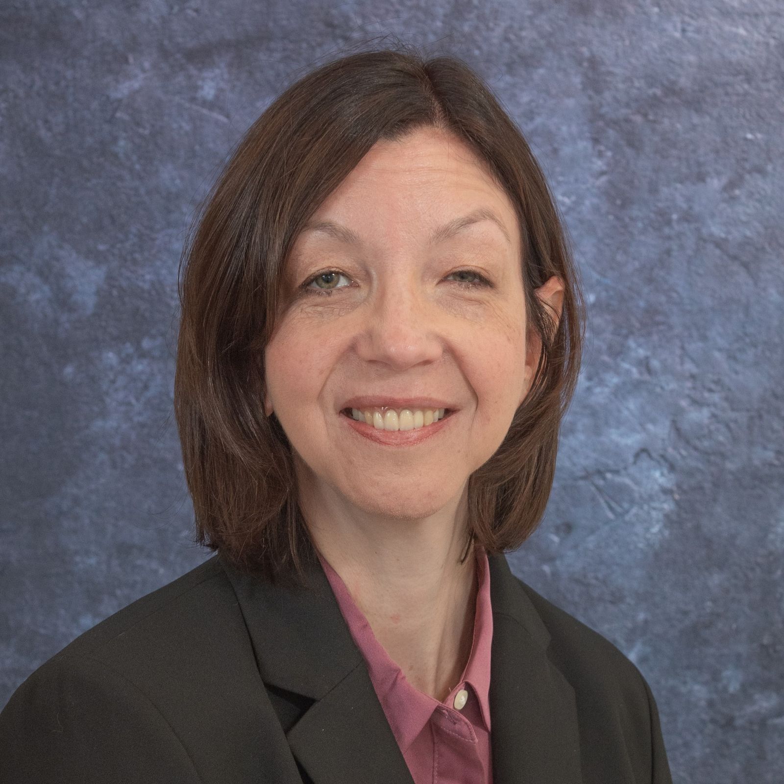 Headshot of Tracy Carver CEO a white woman with shoulder length brown hair and a black blazer