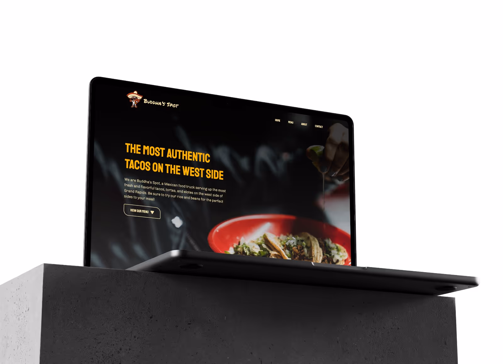 Buddha's Spot home page displayed on Macbook Pro sitting on top of concrete block