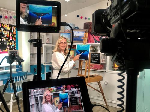 A photo from behind a video camera of Victoria creating a painting tutorial.