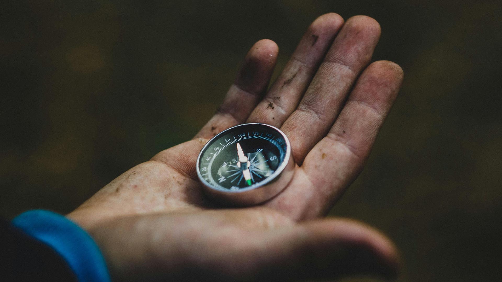 A closeup photo of a hand holding a compass.