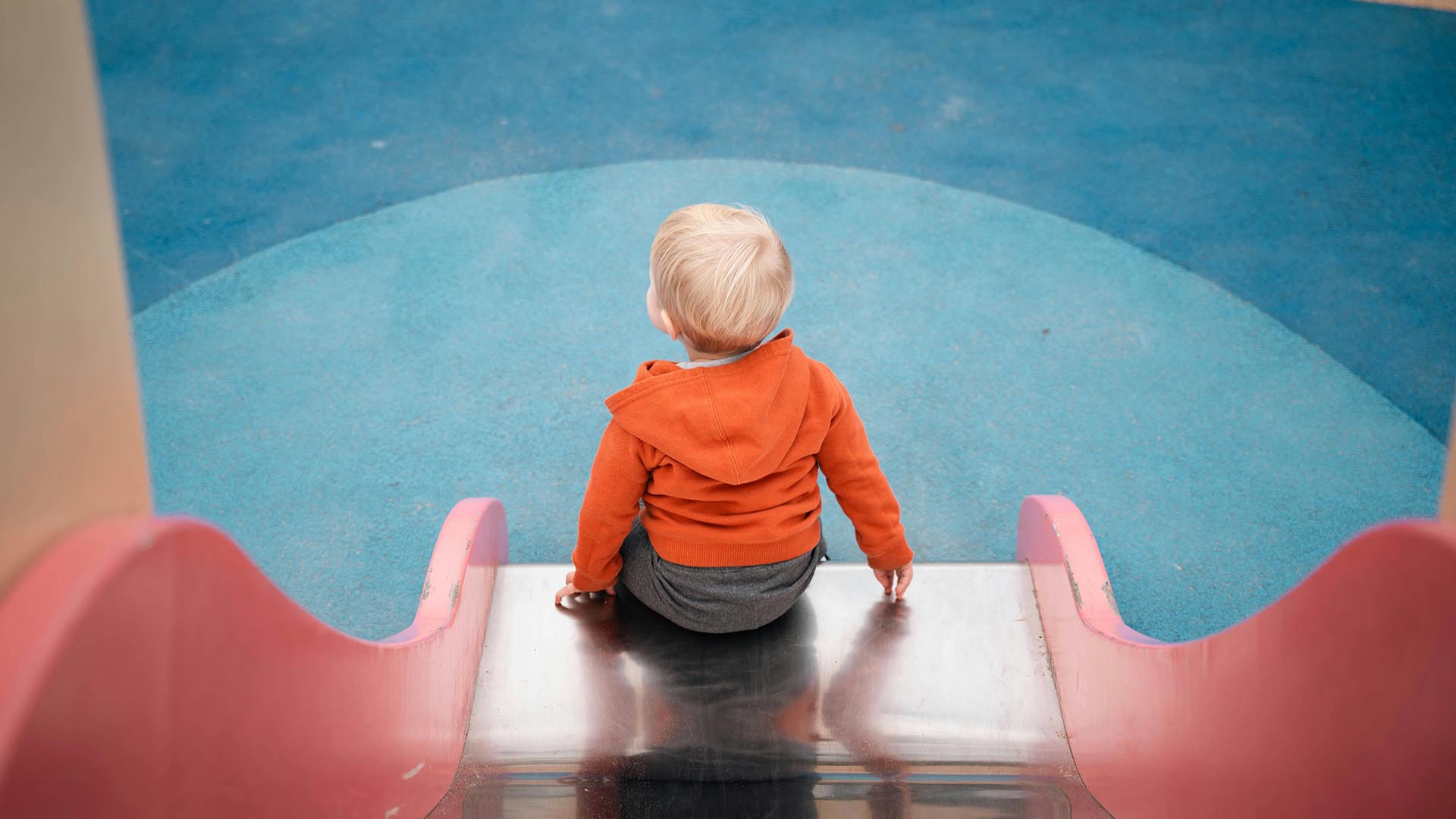 A child playing on a slide in a playground.