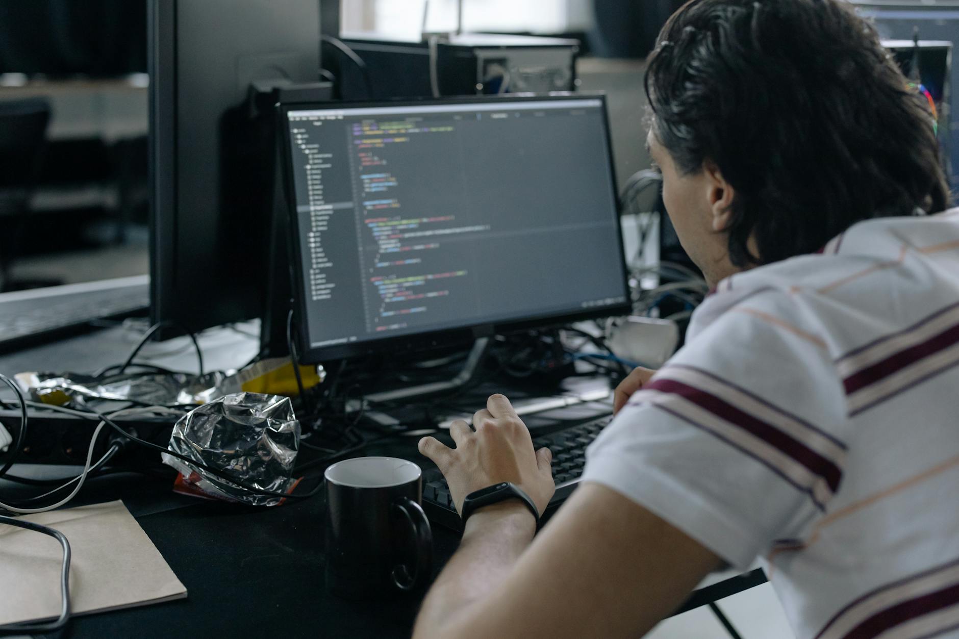 Man focused on coding at his workstation in a modern office.
