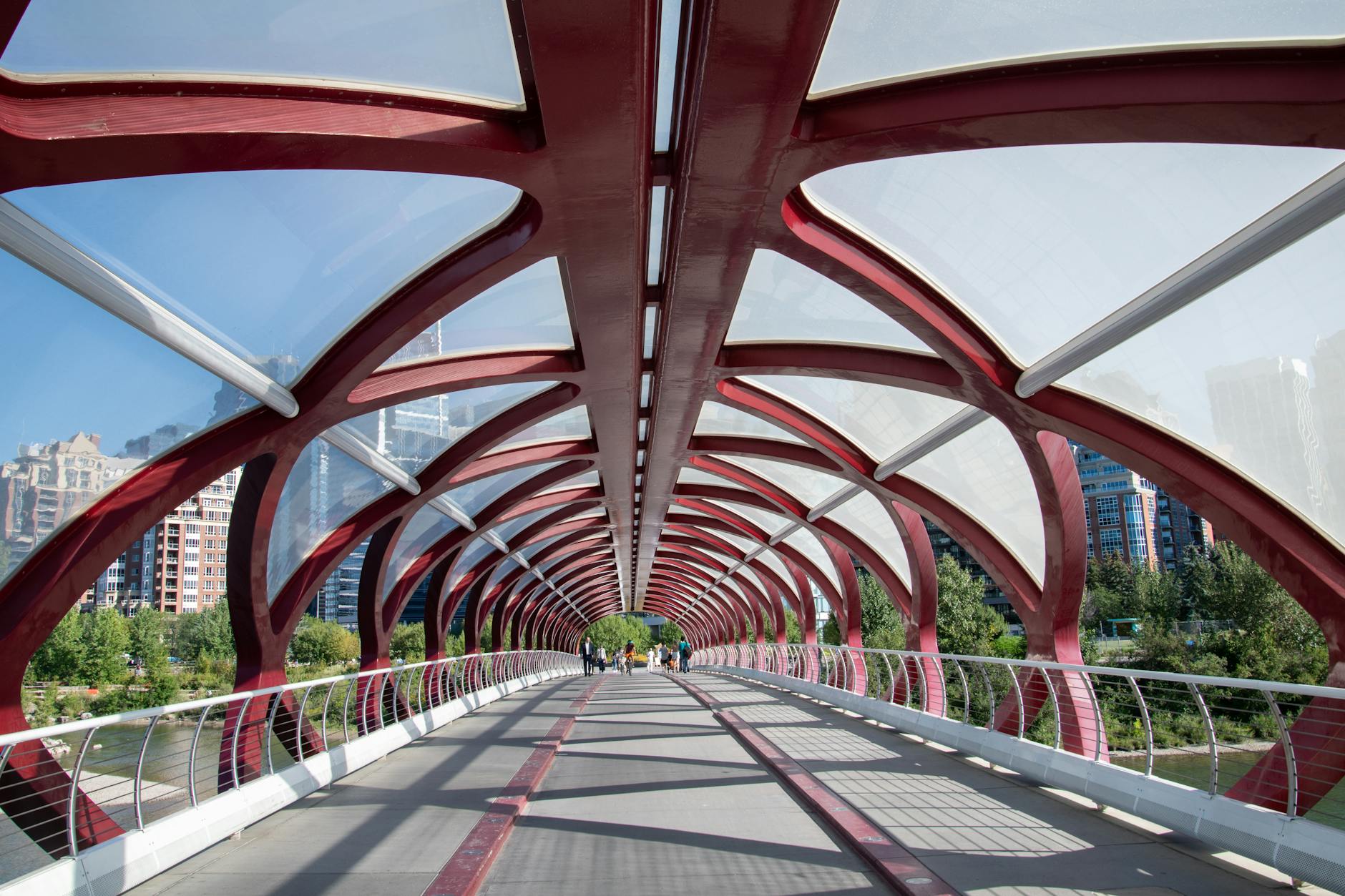 View of the iconic red Peace Bridge in Calgary, Alberta on a sunny day.