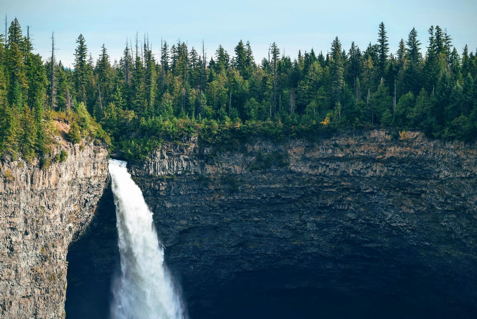 Une chute d'eau tombant d'une falaise dans un canyon boisé