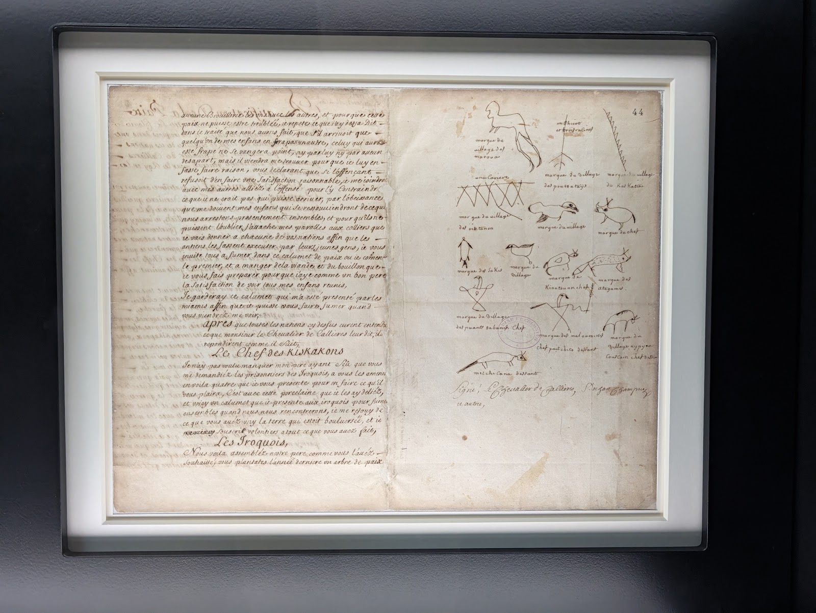A framed manuscript of the 1701 Great Peace of Montreal on display at Pointe-à-Callière, with pictographic signatures in the margin
