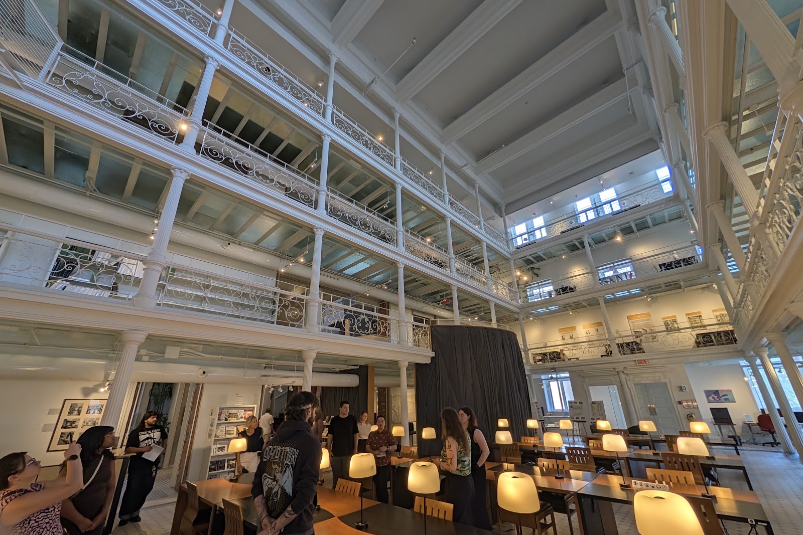 The multi-level reading room at BAnQ's Archives nationales à Montréal, with white iron balconies, a skylight and long wooden study tables