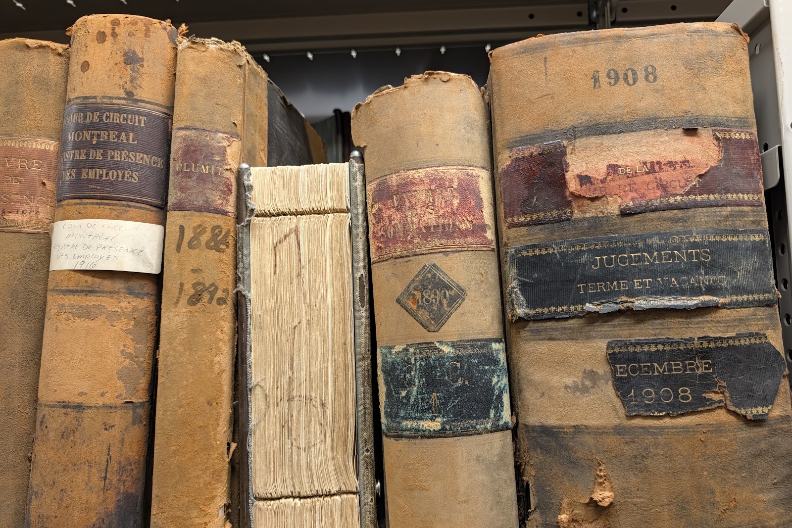 Worn leather-bound court registers on a shelf, one spine dated 1908
