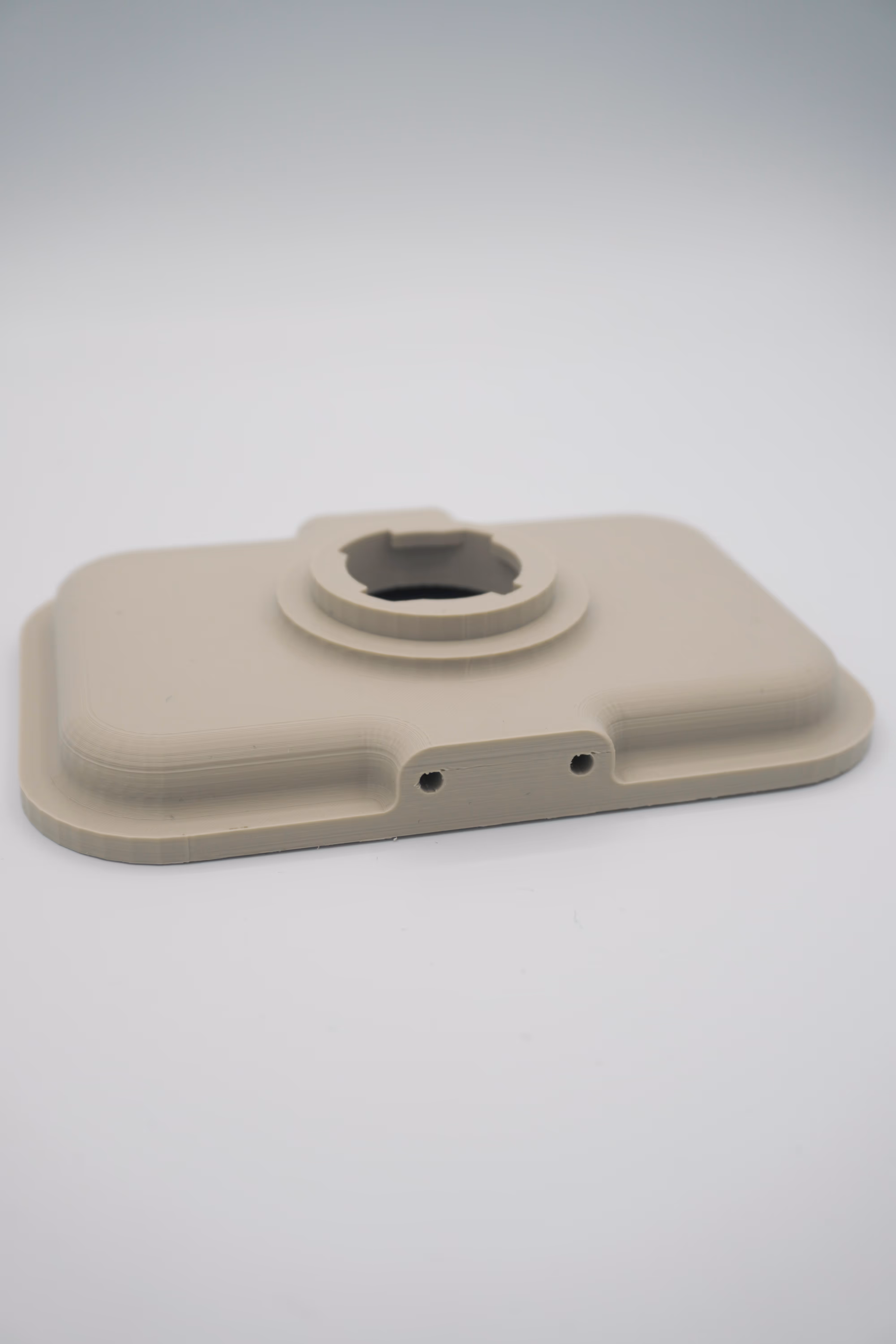 Beige 3D-geprint rechthoekig paneel met afgeronde hoeken, een centraal rond bevestigingselement en twee montagegaten