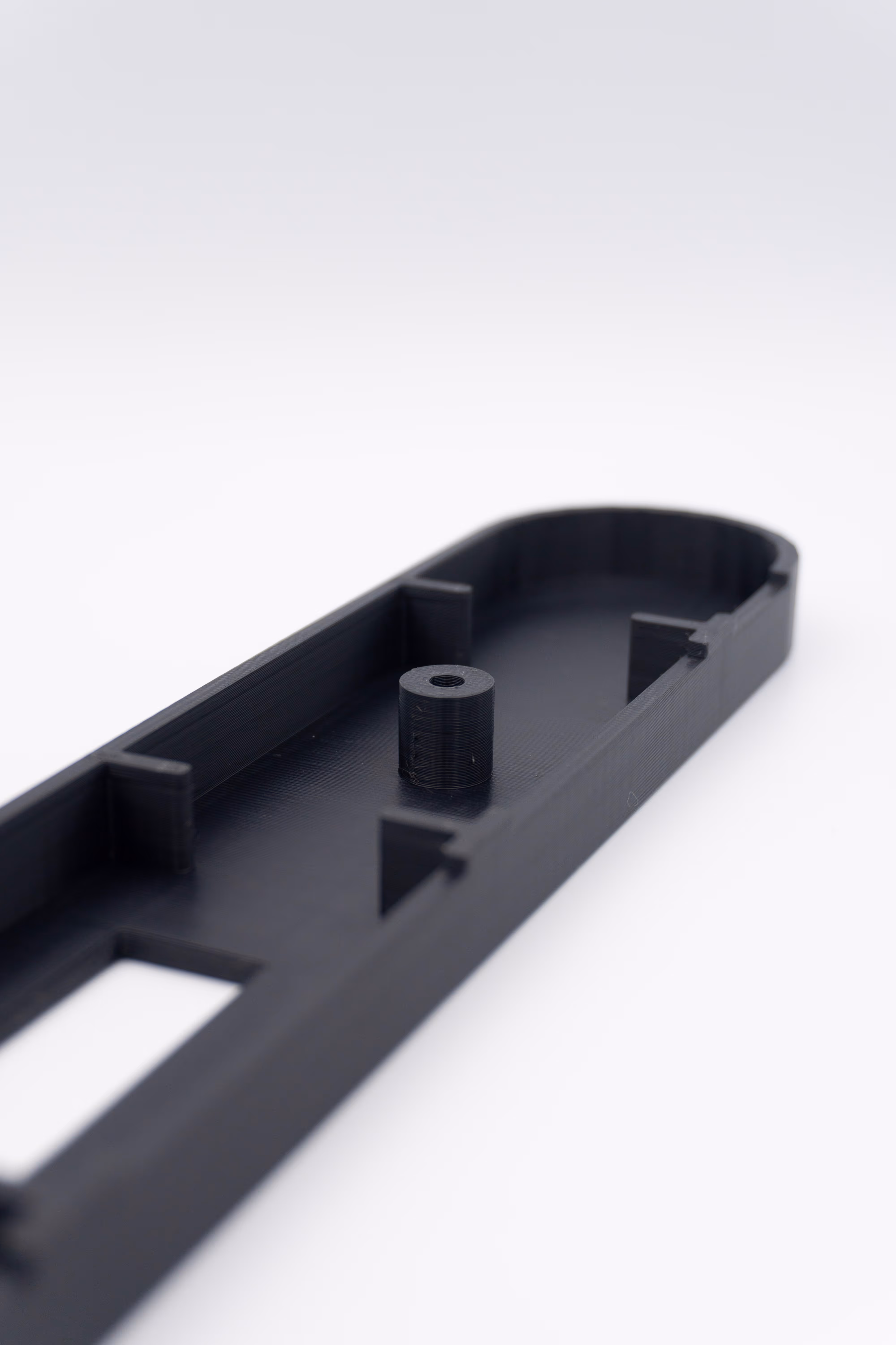 Zwart 3D-geprint onderdeel met cilindrische verhoging op witte achtergrond