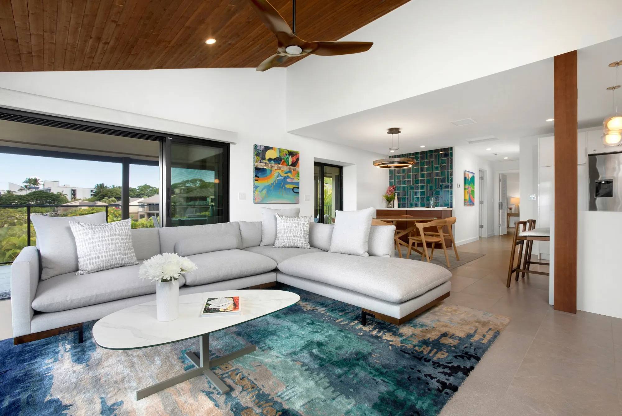 Wailea Elua living and dining room with pale sectional, blue rug and colorful artwork
