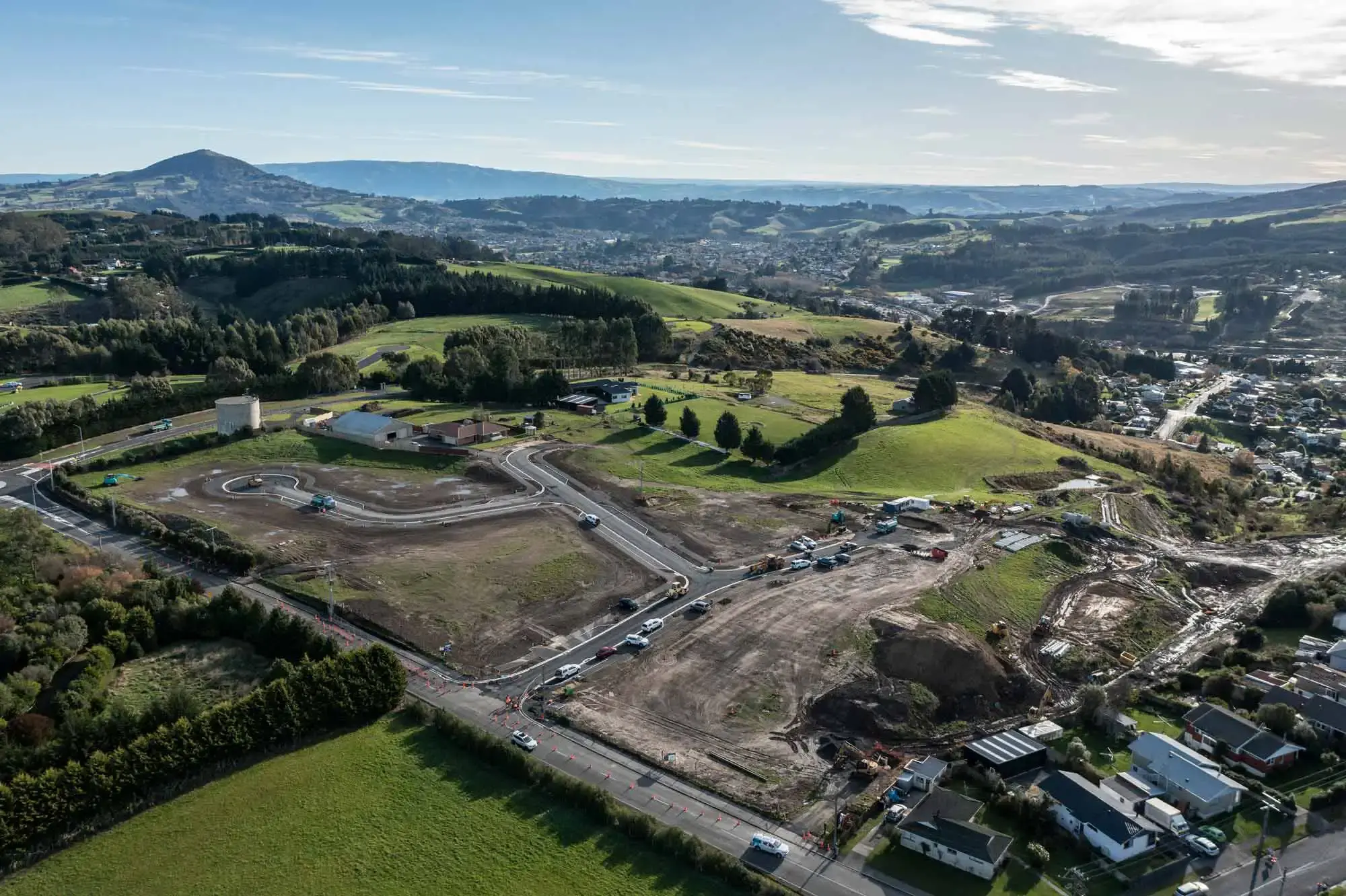 Modern single-story house with illuminated large windows and a ramped wooden walkway leading to the front door at dusk.