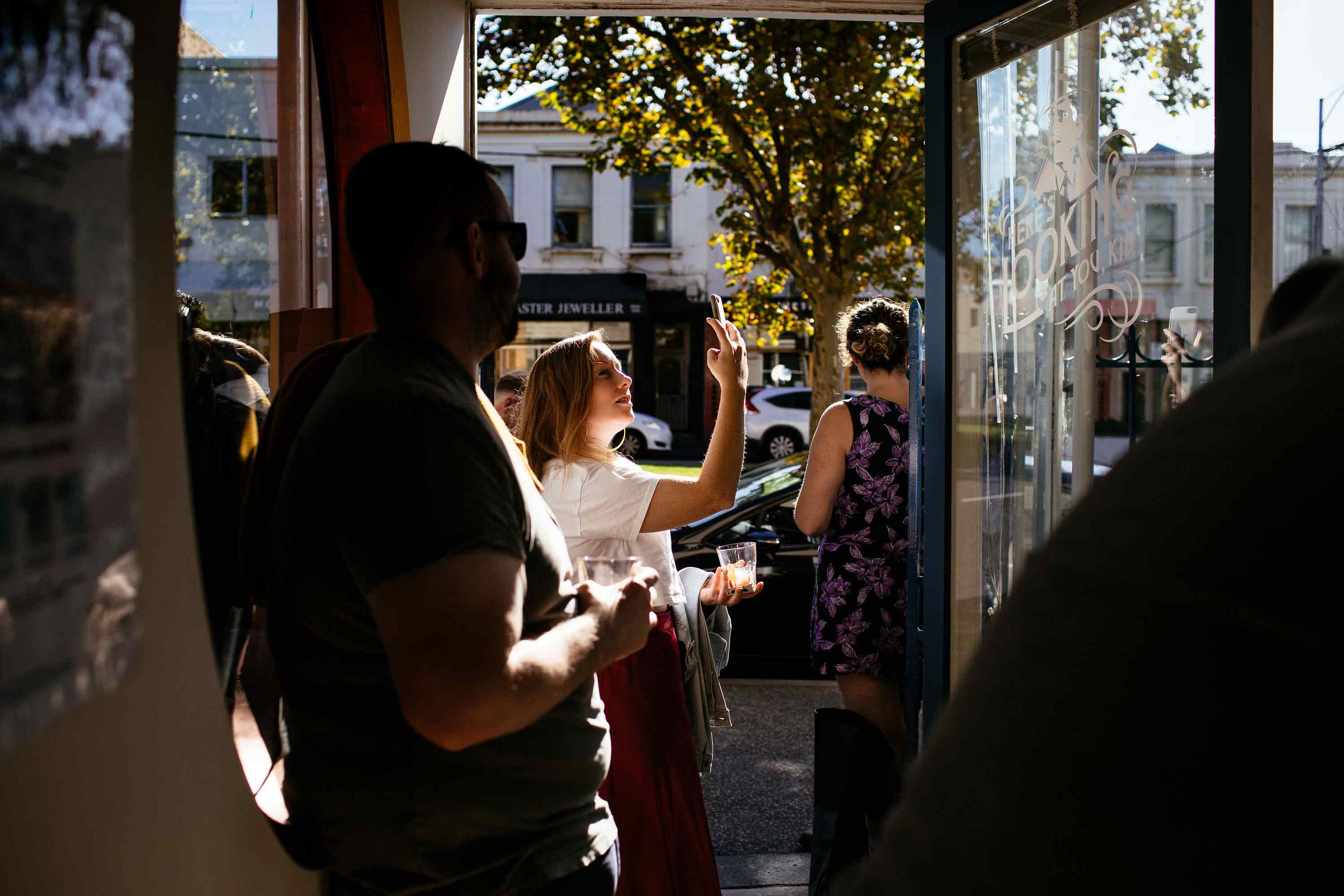 Customer photographing hand-painted hospitality signage, demonstrating memorable brand experiences and social sharing.
