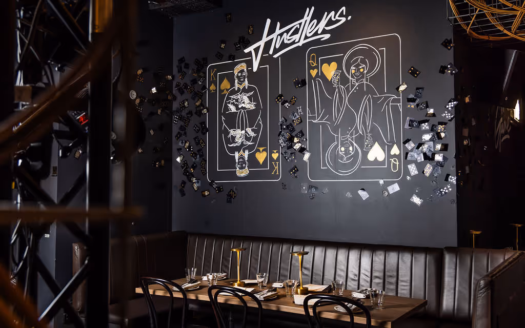 Private dining booth at Hustlers Sydney, underground functions venue, with branded chalkboard art and moody lighting.