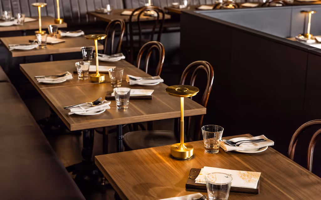 Cozy two-top booth with gold lamps and timber table inside Hustlers Sydney functions space.