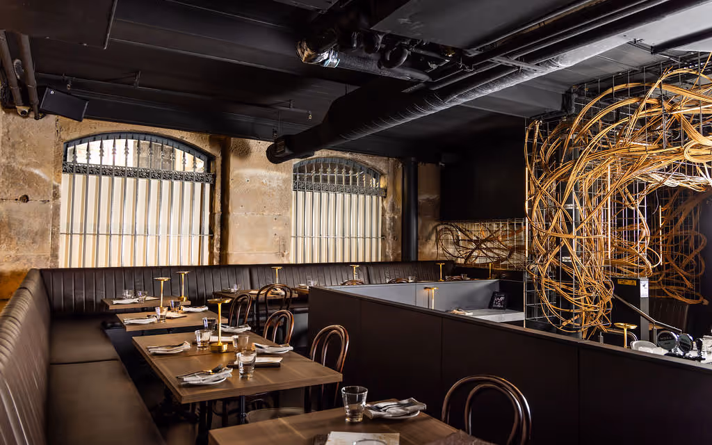 Wide view of Hustlers Sydney event floor showing multiple booths, sculptural décor and sandstone walls ready for large bookings.