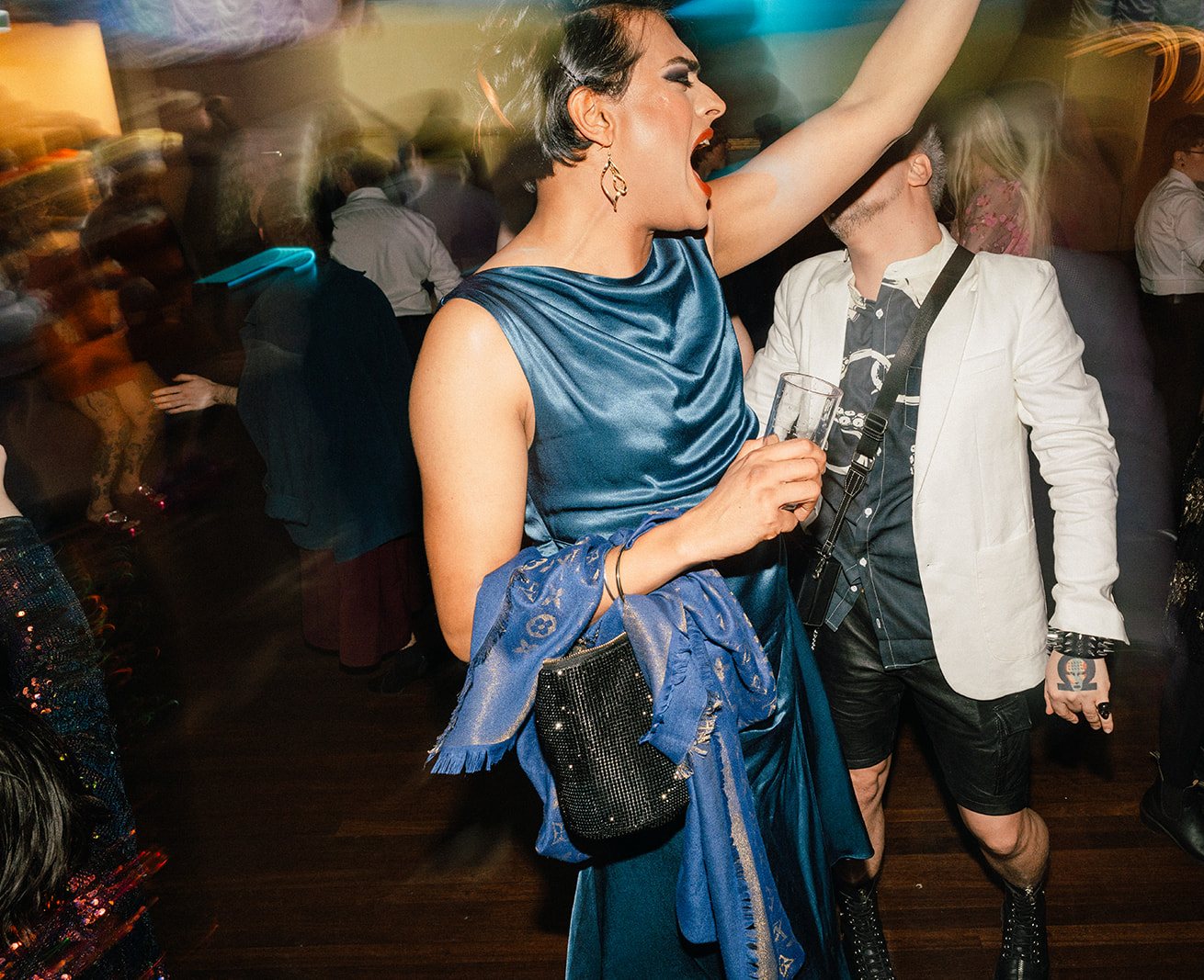 A guest in a blue satin dress dancing with a hand in the air