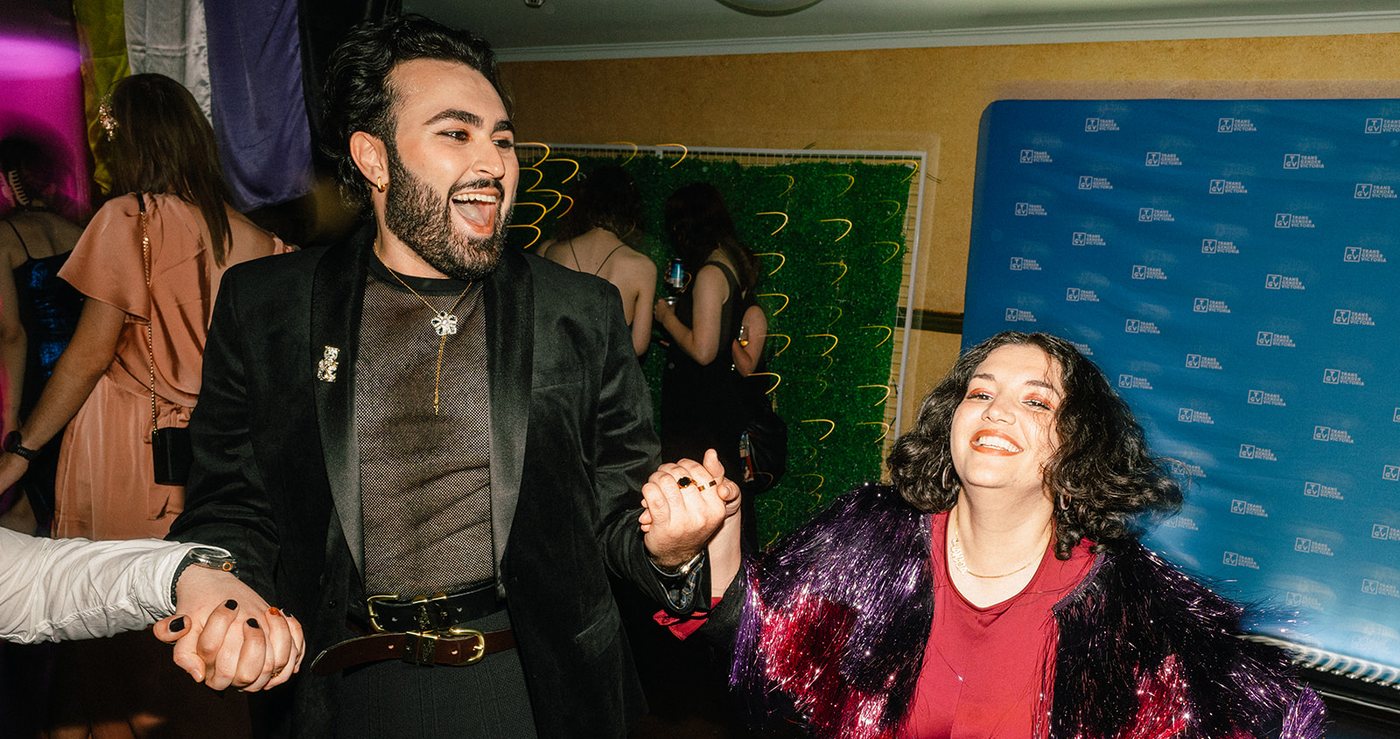 Two guests dancing hand in hand, one in a black suit and one in a red sequin dress