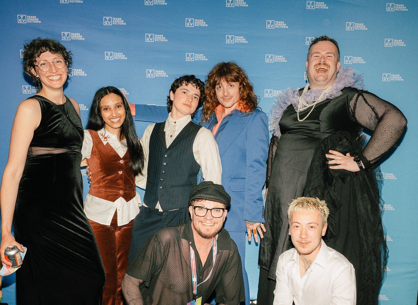 Seven guests dressed up and posing together in front of the media wall at the Gala