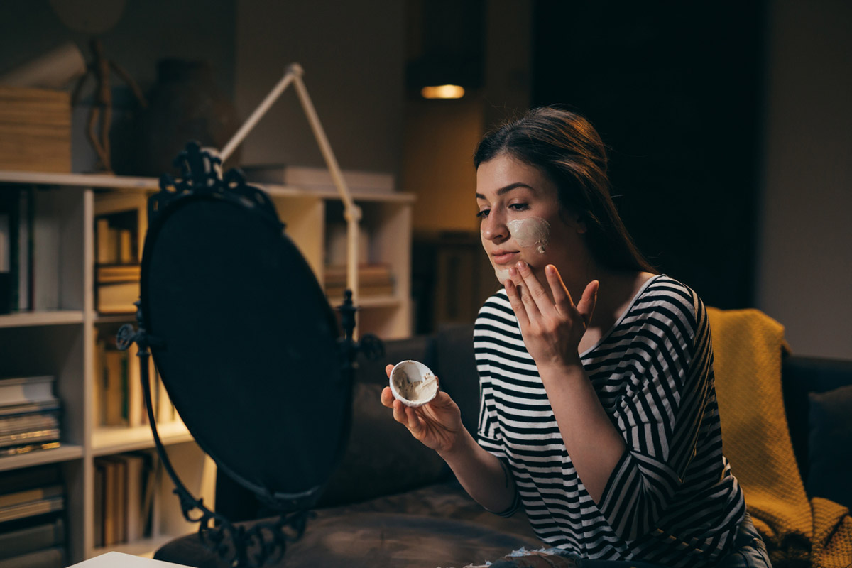 A young woman applies a nighttime skin cream before bed. 