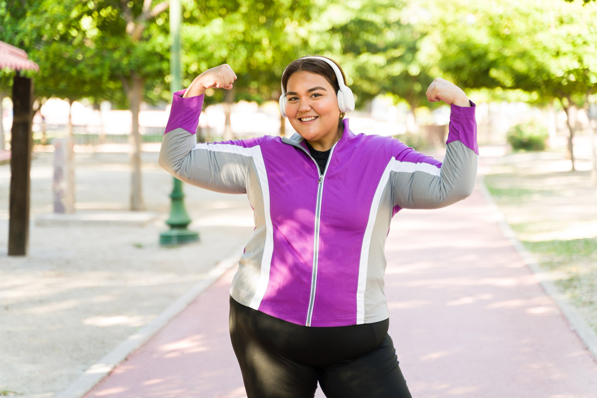 A woman on a GLP-1 medication flexes her arm muscles during a workout.