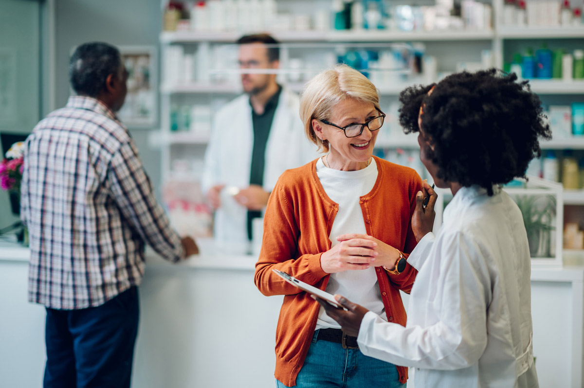 An independent pharmacy owner helps a patient with their medication. 