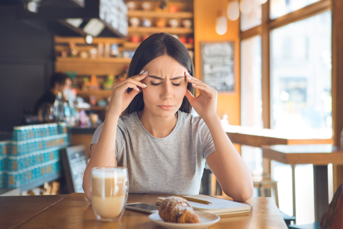 A woman who has had too much caffeine suffers from a headache.