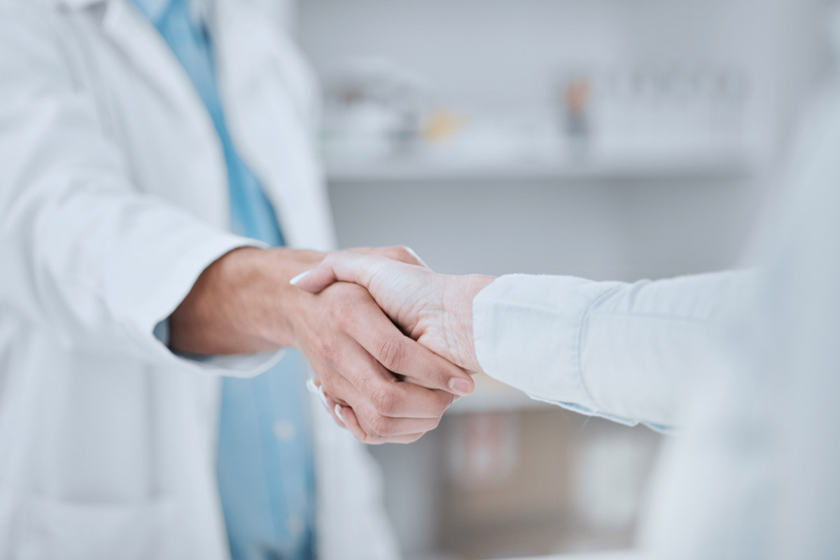 A doctor and pharmacist shake hands.