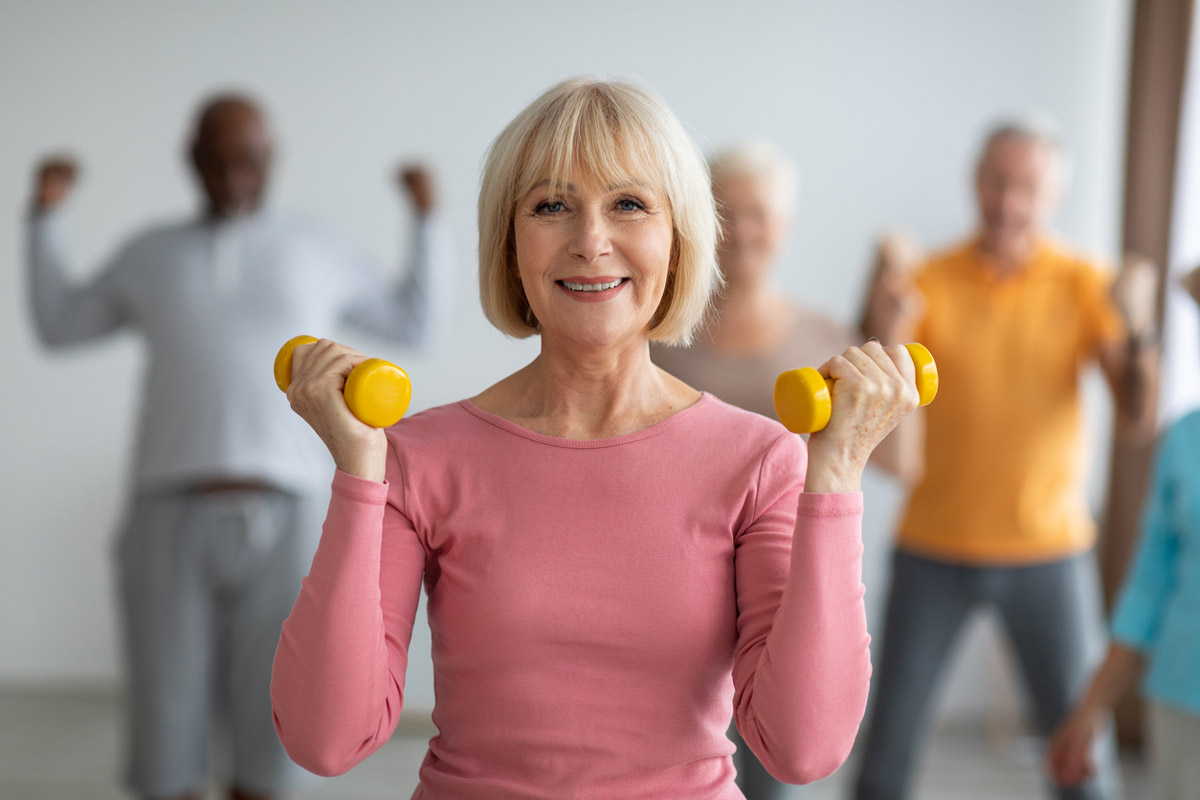 An elderly woman does light weight training to improve her heart health. 