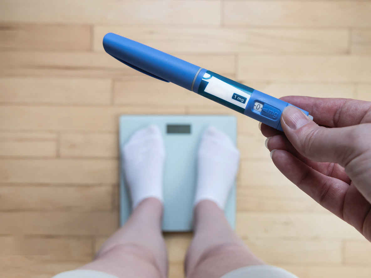A patient who takes a GLP-1 medication weighs in while holding their latest dose of GLP-1.