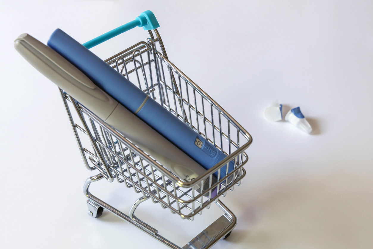 A mini shopping cart holds a GLP-1 injector pen.