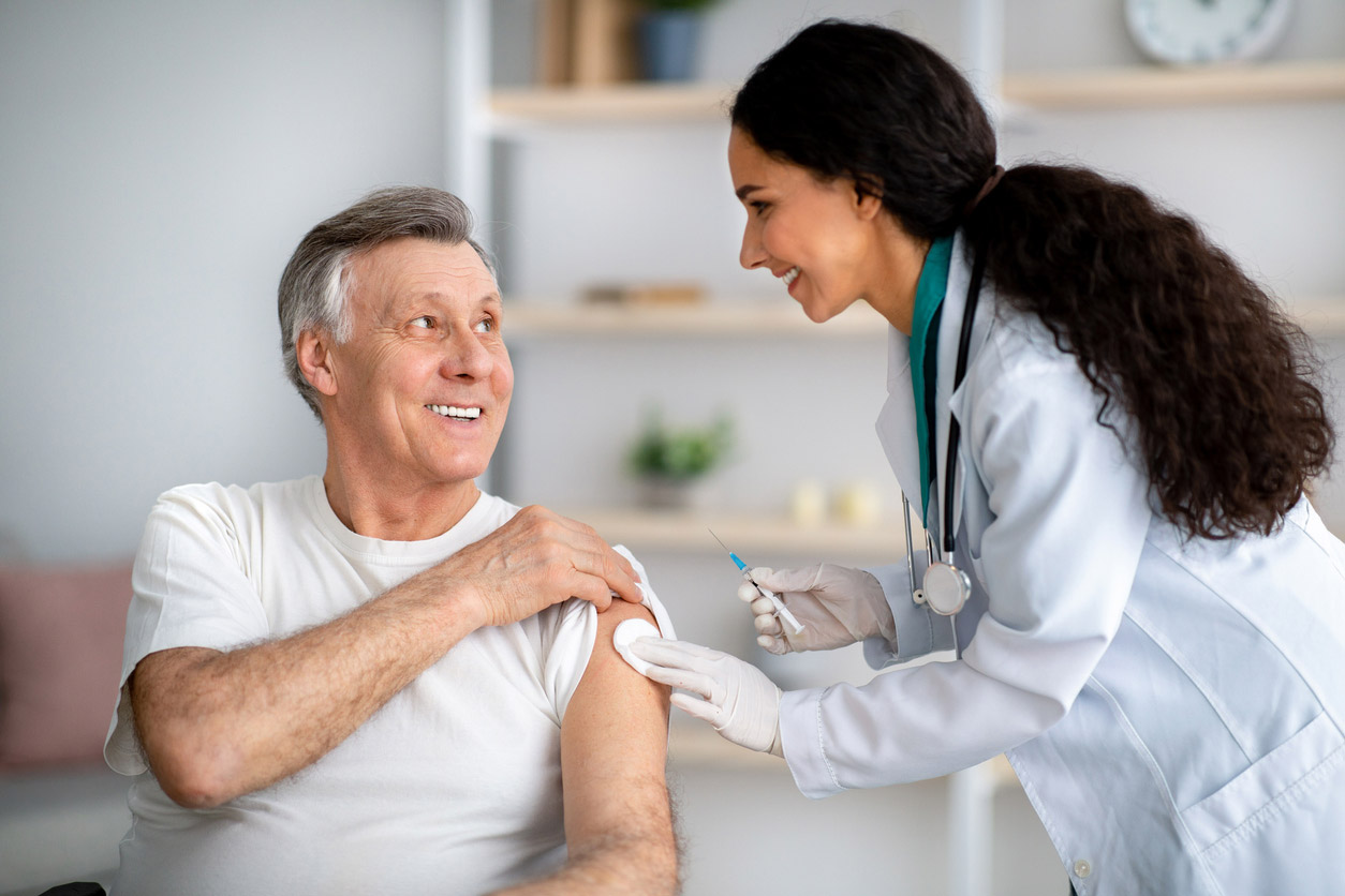 A pharmacist gives an older patient a vaccine. 