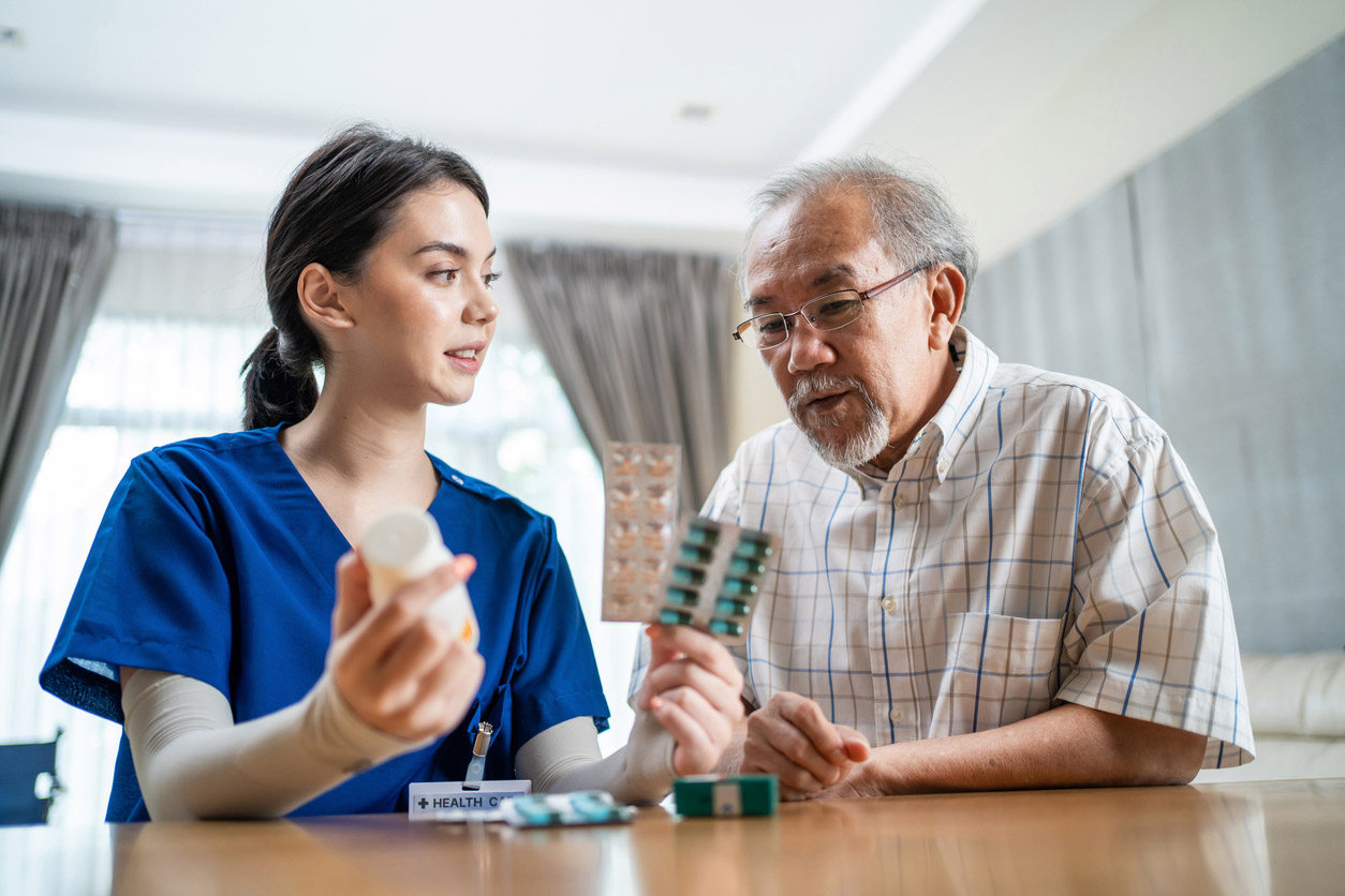 A pharmacist covers medication details with an elderly patient. 
