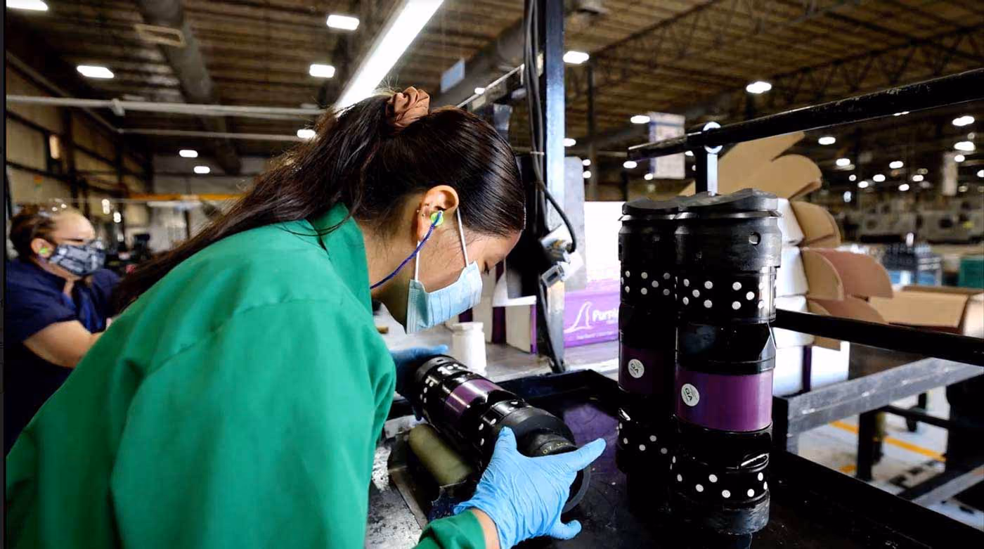 A production worker meticulously inspects a frac plug or other downhole completion tool.