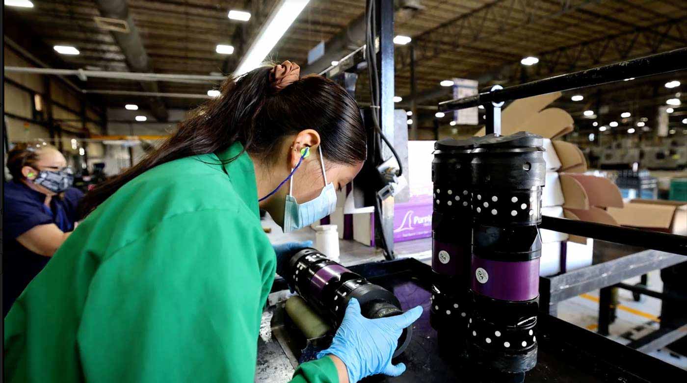 A production worker meticulously inspects a frac plug or other downhole completion tool.