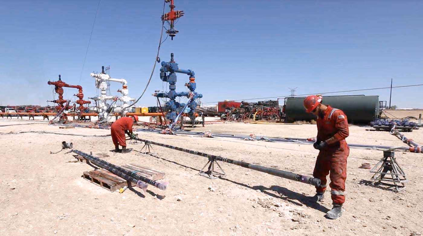 Two field workers using frac plugs and other downhole completion tools in the field.