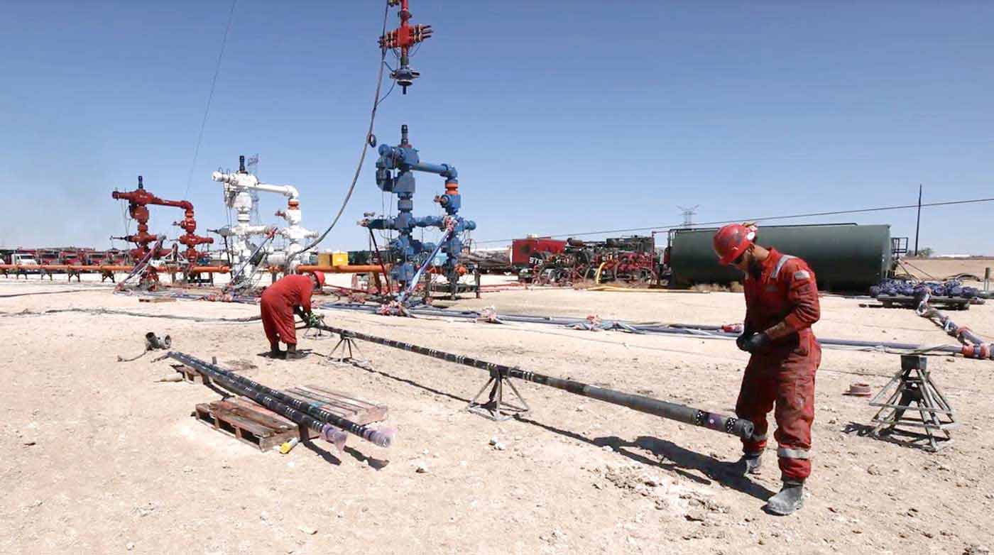 Two field workers using frac plugs and other downhole completion tools in the field.