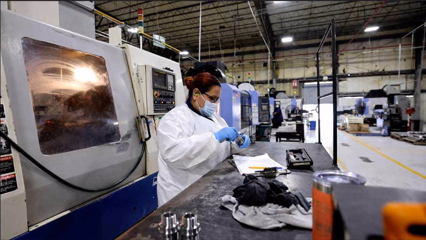 A frac plug and downhole completion tools manufacturing worker meticulously inspects the quality of a product.