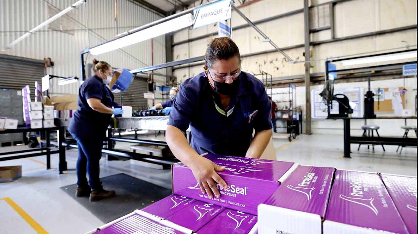 A worker stacking boxes of frac plugs and other downhole completion tools.