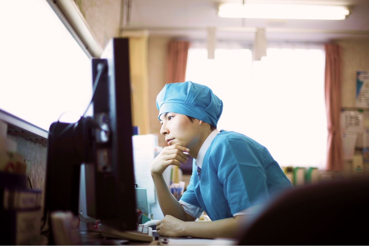 Image of a man in medical scrubs looking at a computer screen